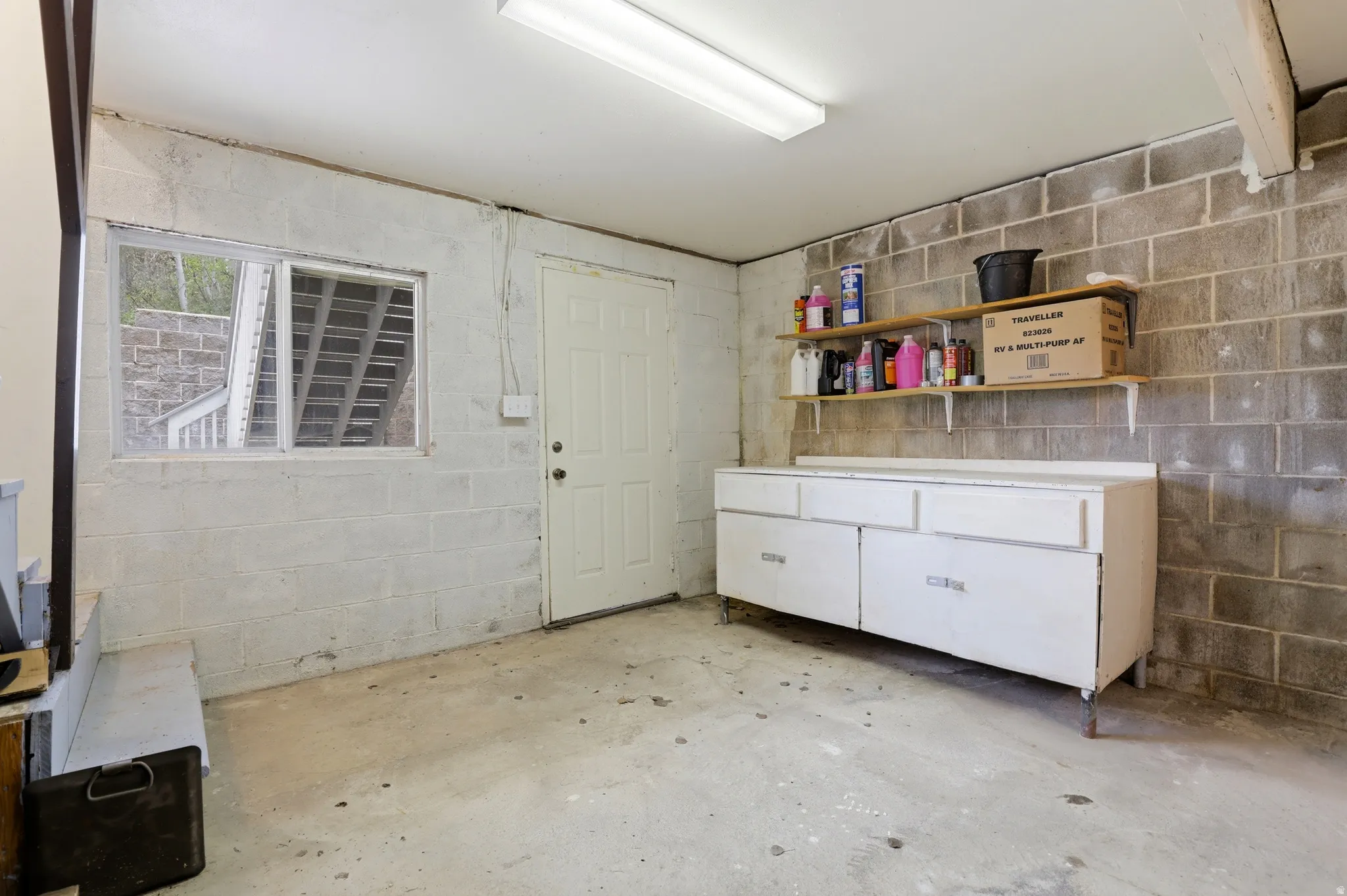 Utility room featuring exposed concrete block walls and a concrete floor
