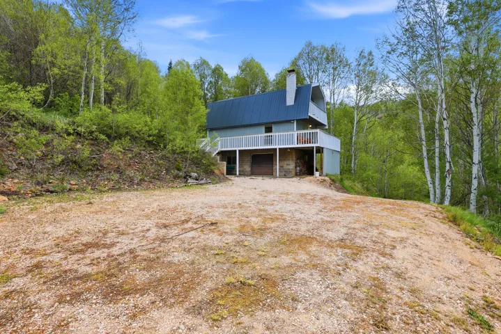 Two-story residence featuring a blue metal roof, light blue siding, and a stone-clad lower level
