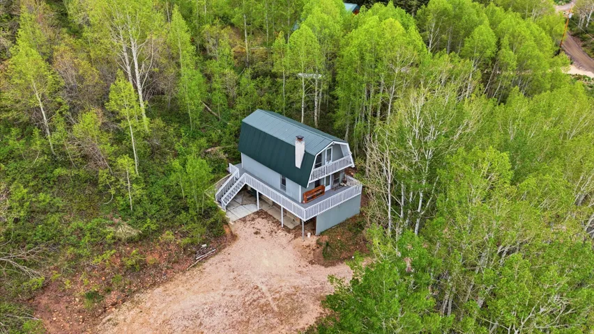 Gambrel roofline property surrounded by mature trees