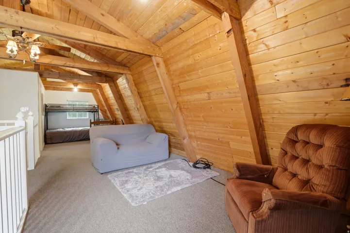 Open loft area featuring exposed wood beams and wood-paneled walls