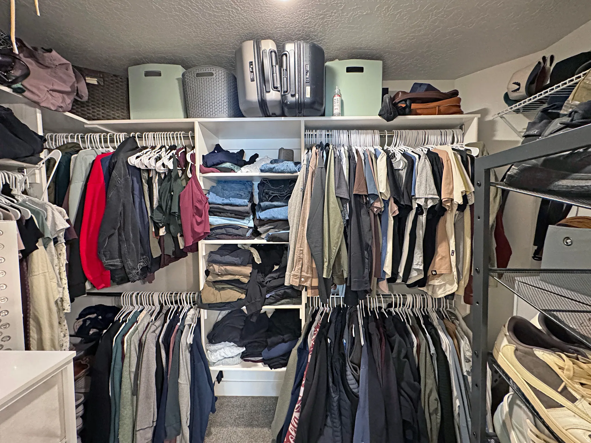 Walk-in closet featuring white built-in shelving, multiple hanging rods, and integrated open storage