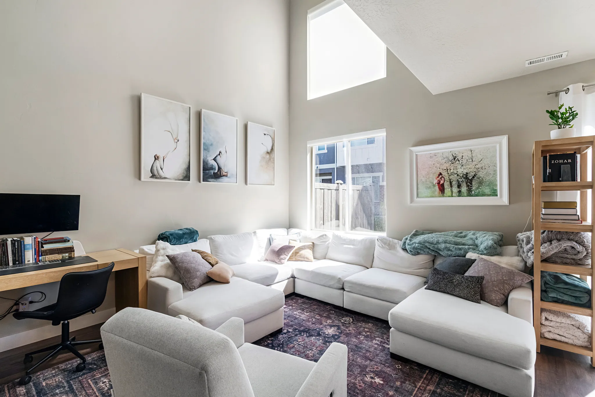 Living area featuring high ceilings, a prominent transom window, wood-finish flooring, and light-toned walls