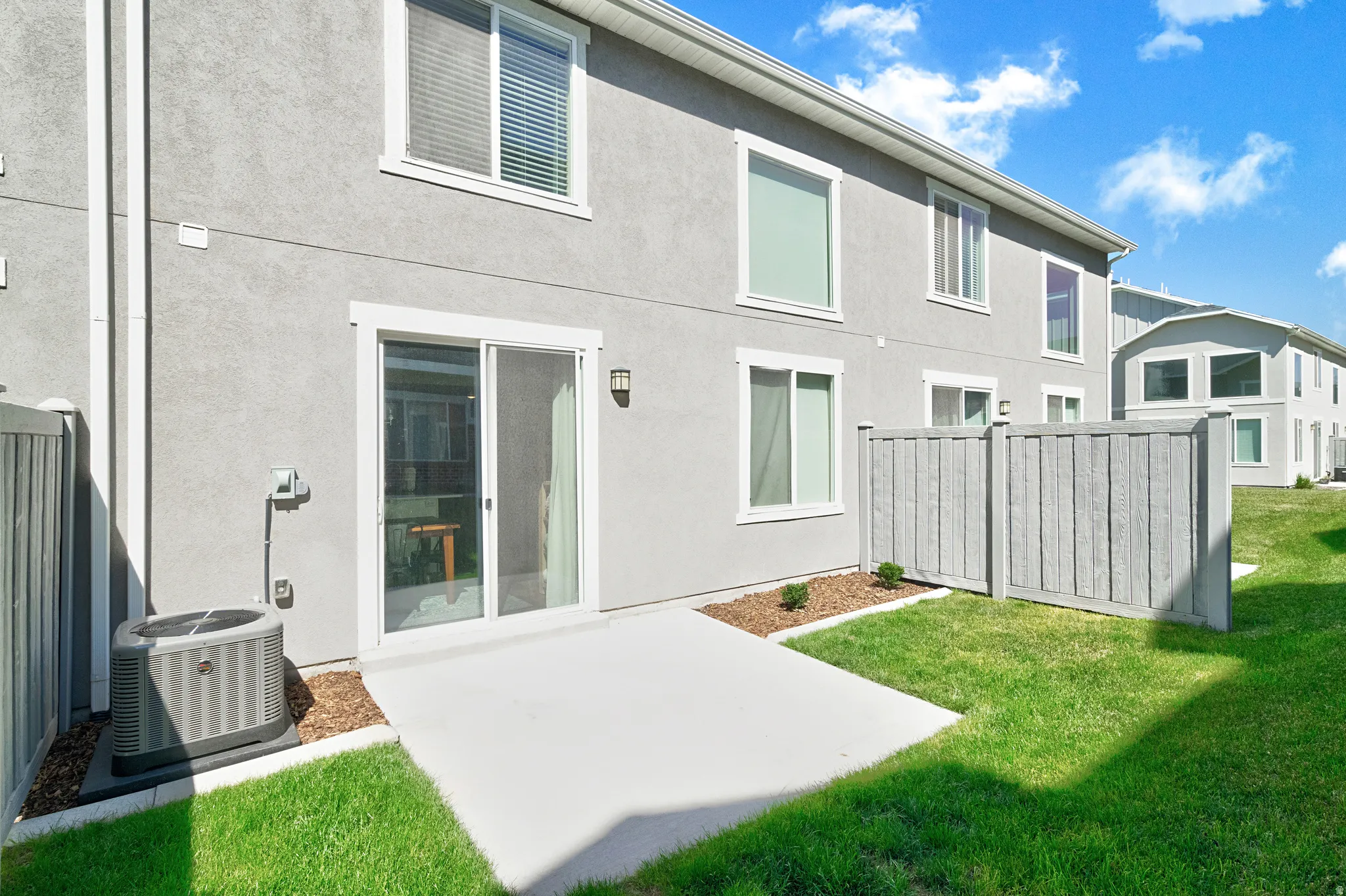 Rear patio area featuring a concrete slab, sliding glass door, and exterior sconce lighting