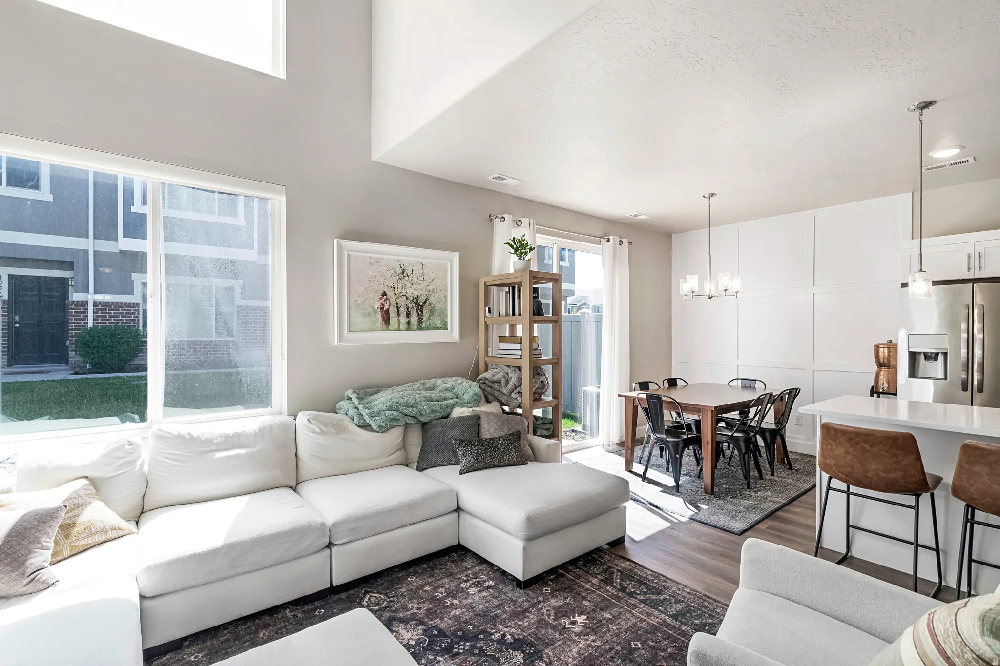 Open-concept living space featuring high ceilings, wood-finish flooring, and expansive windows