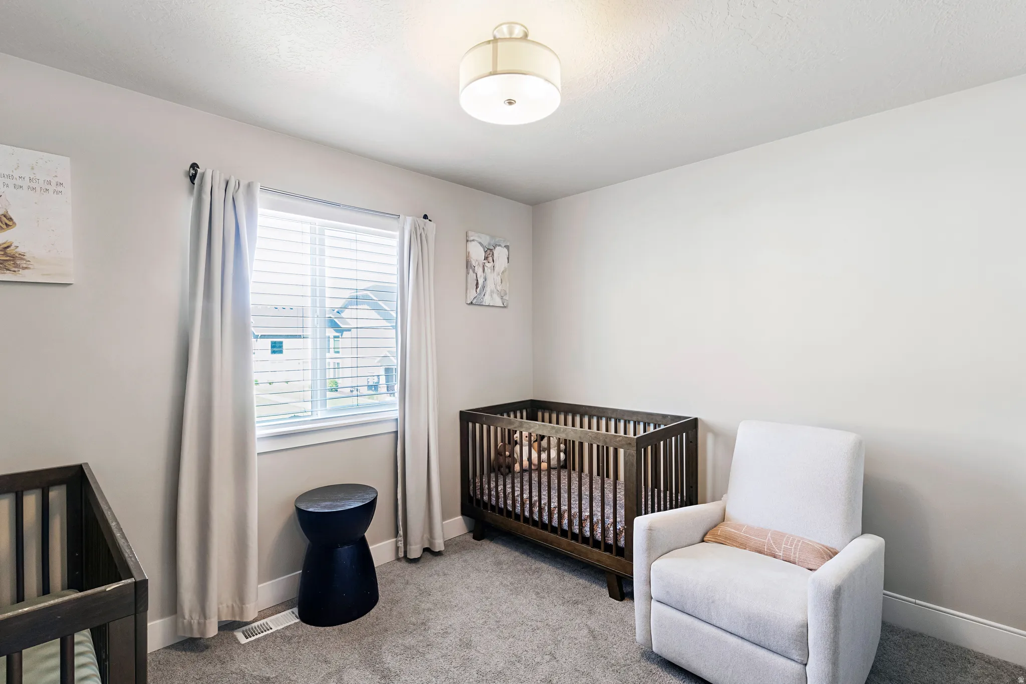 Carpeted room with a double-paned window featuring blinds and light-colored curtains