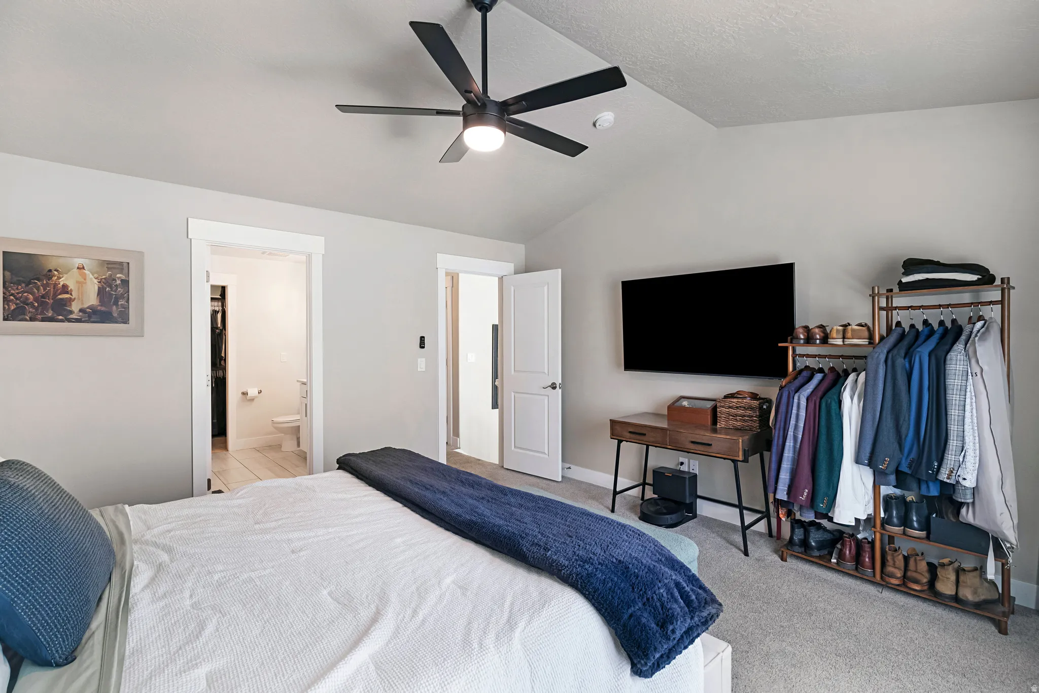 Spacious room featuring vaulted ceilings, light-toned carpeting, a modern ceiling fan with integrated lighting, and two interior doorways with white trim