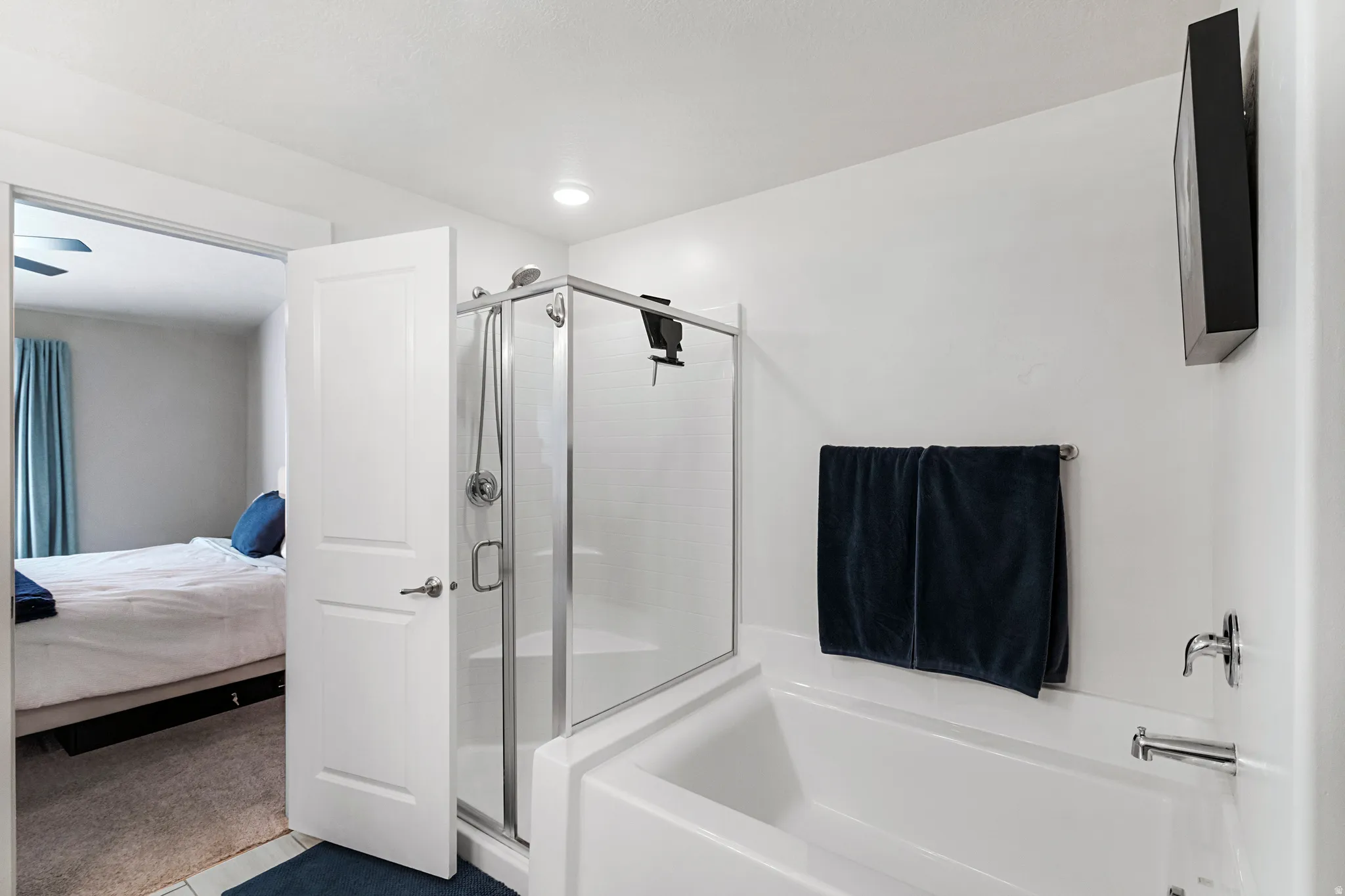 Bathroom featuring a built-in tub, a glass-enclosed shower with a handheld showerhead, and chrome fixtures