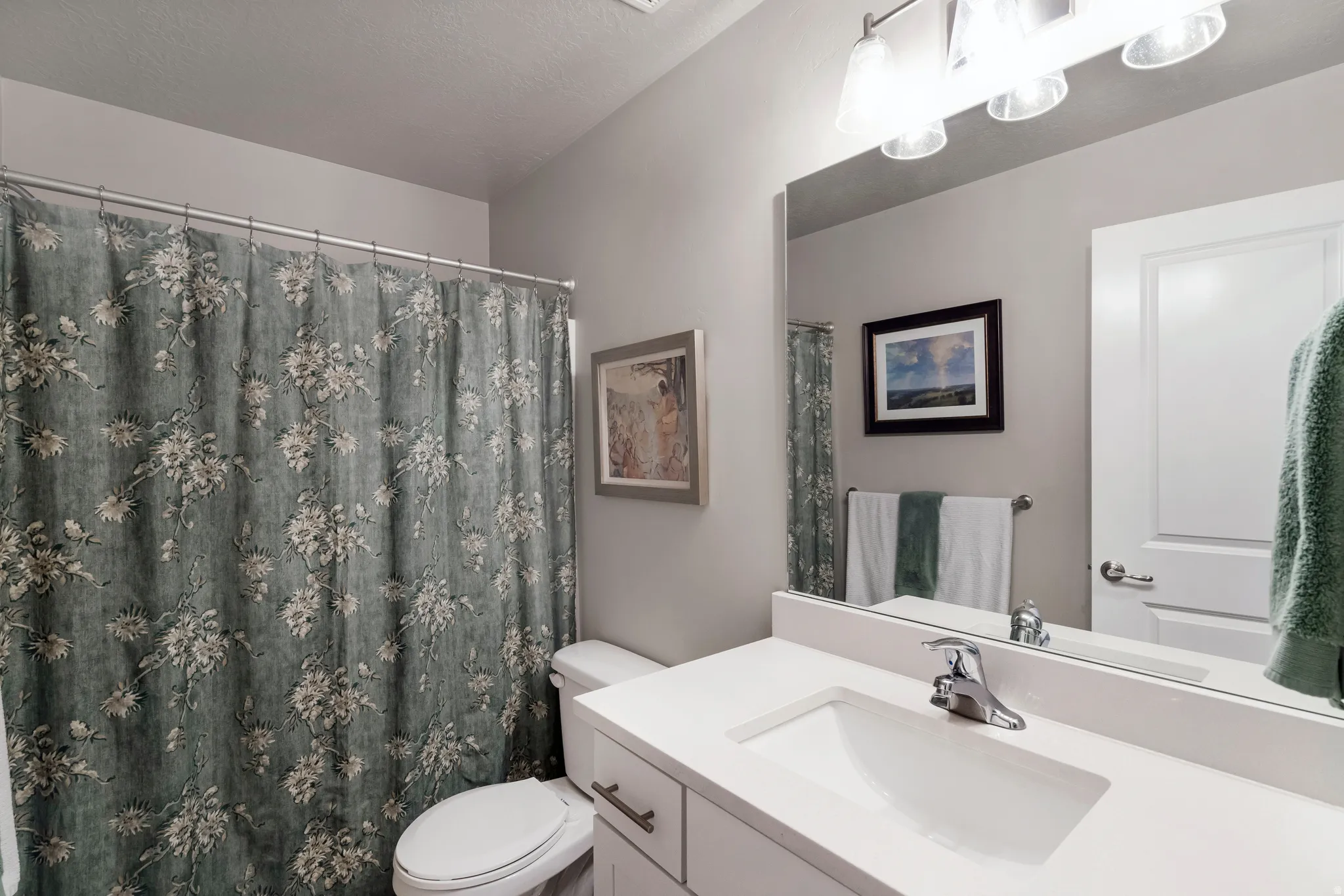 Bathroom featuring a white vanity with an integrated sink, chrome faucet, and a large mirror