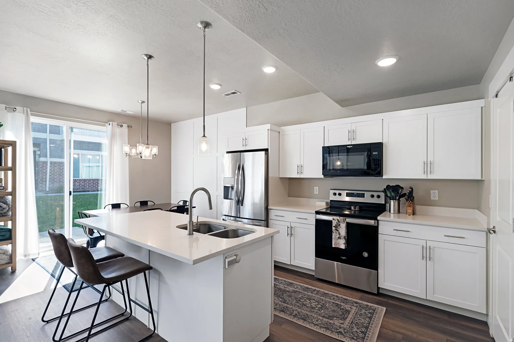 Modern kitchen featuring white cabinetry, light-toned countertops, stainless steel appliances, and wood-finish flooring