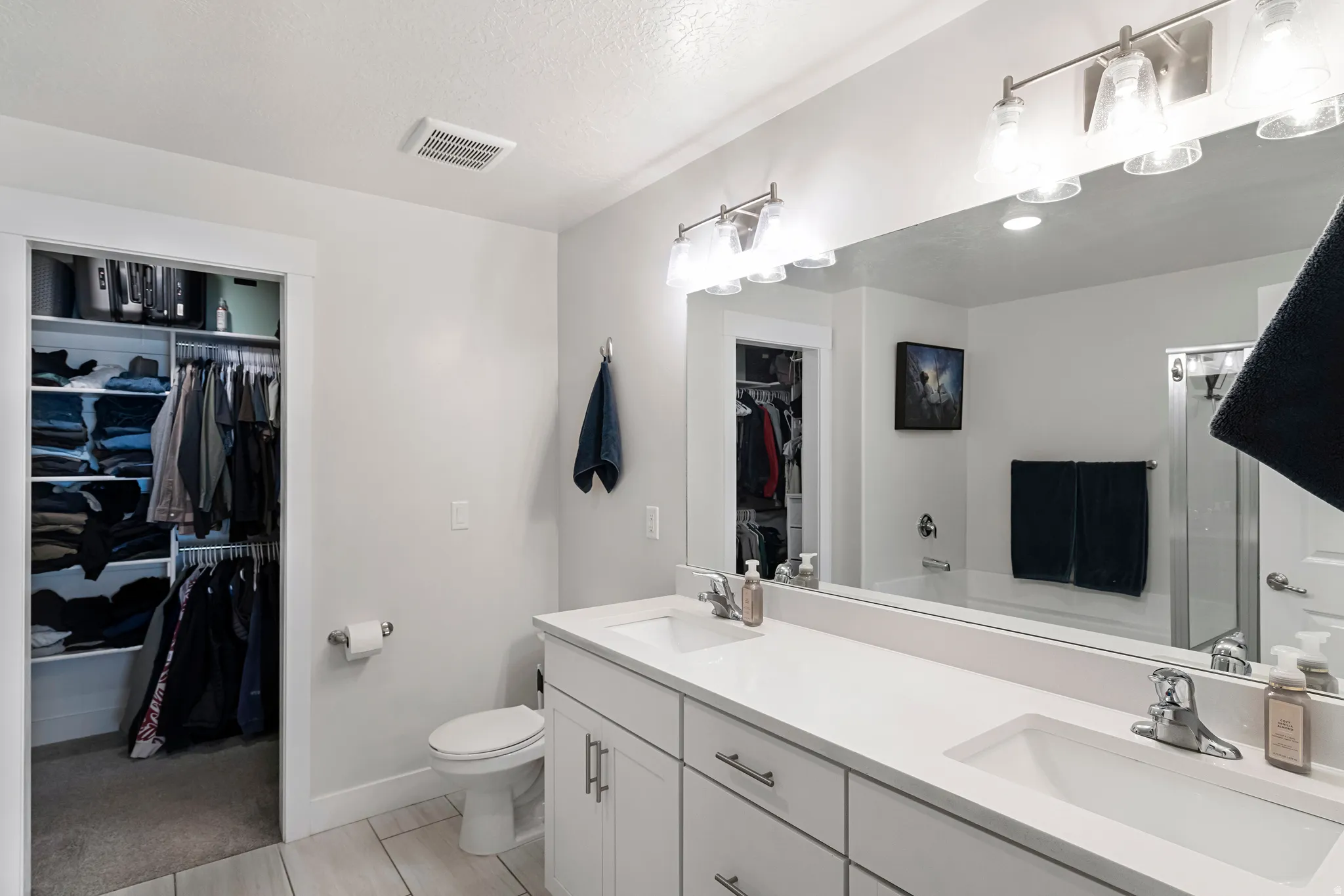 White double vanity with integrated sinks, brushed nickel fixtures, and a large wall-mounted mirror