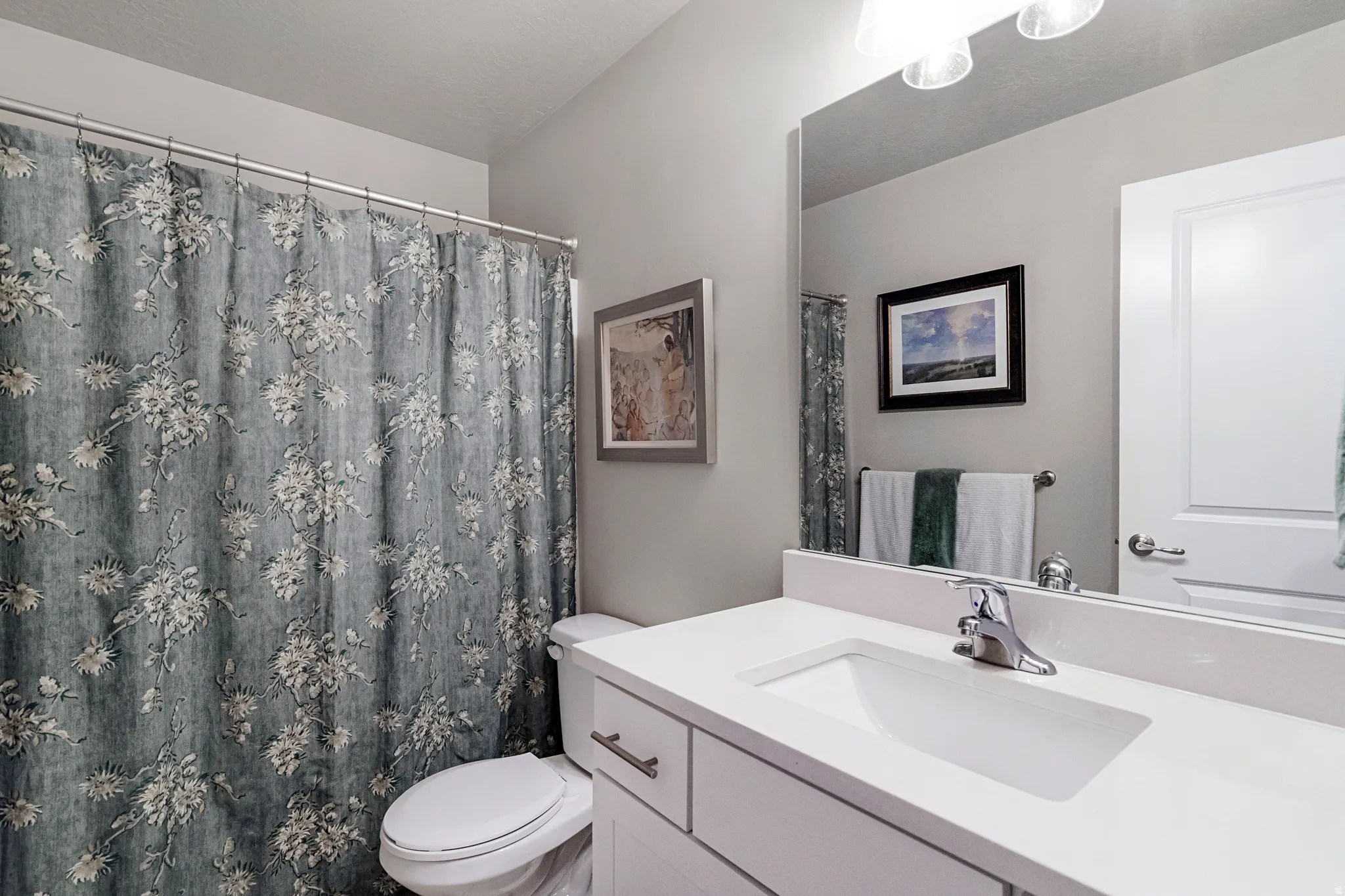 Bathroom featuring a white vanity with an integrated sink, chrome faucet, and a large wall-mounted mirror