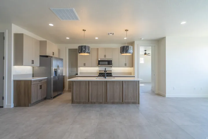 Contemporary kitchen featuring a large center island with a sink, stainless steel appliances, and overhead pendant lighting