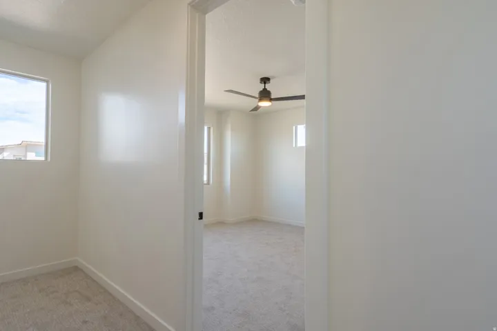 Interior room featuring light-colored carpeting, white wall finishes, and a window providing natural illumination