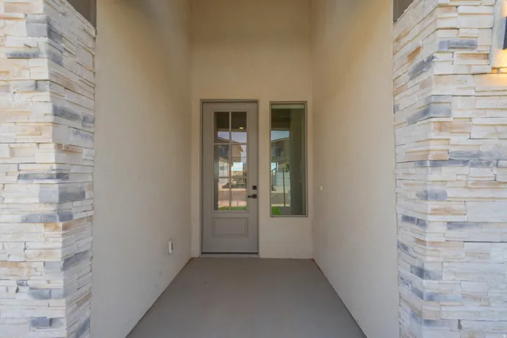 Recessed entryway featuring a stucco finish, stacked stone accents, a full-lite door with divided lites, and a sidelite window
