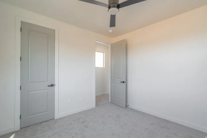 Bedroom featuring light grey carpeting, white walls, and a modern ceiling fan with integrated lighting