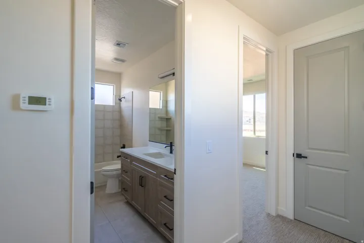 Full bathroom featuring a wood-finish vanity with a white countertop and rectangular undermount sink