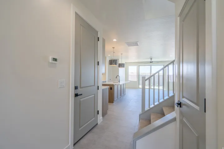 Entryway featuring a modern gray door with black hardware, a light gray wall, and a programmable thermostat