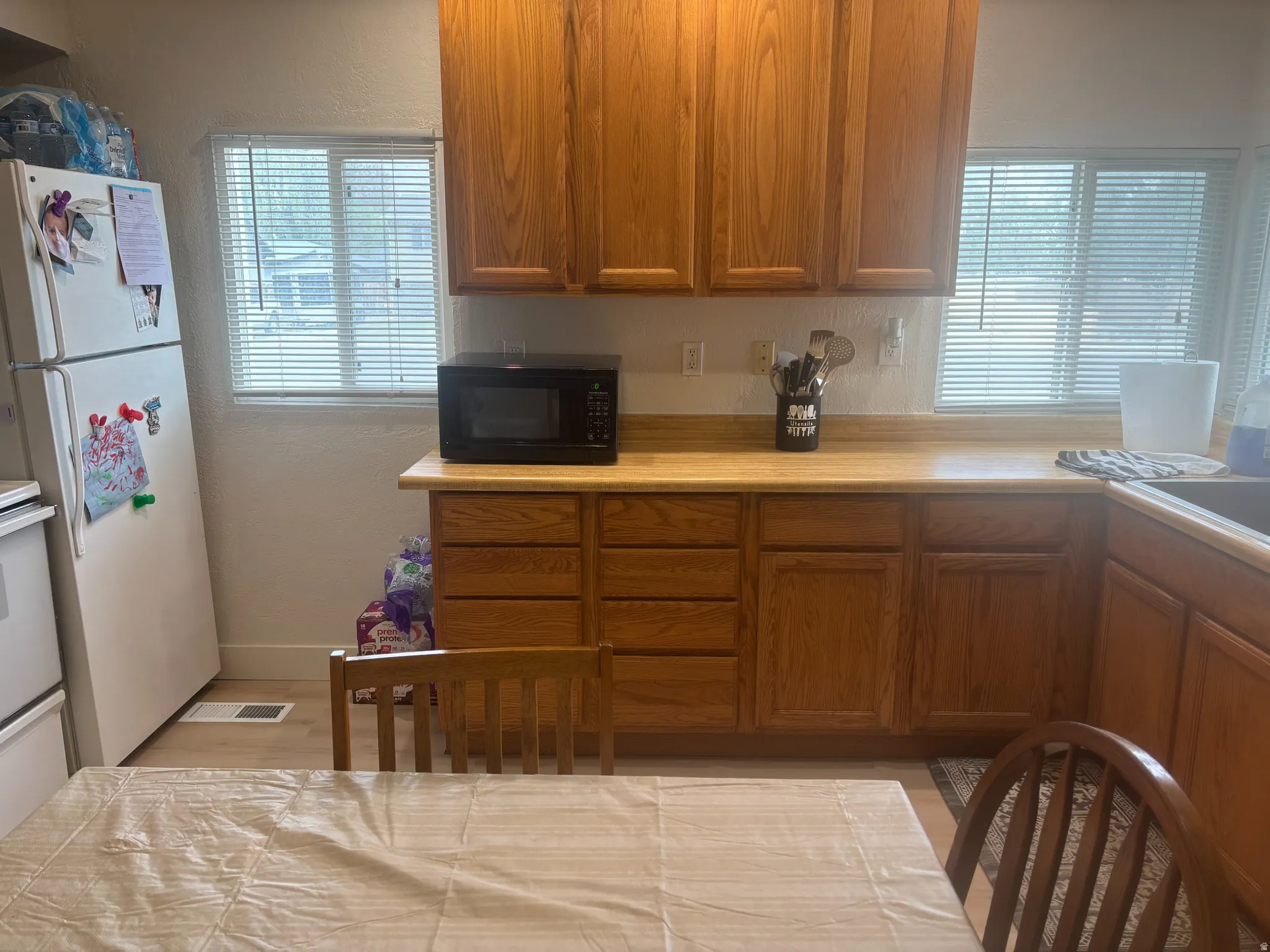 Kitchen featuring wood-finish cabinetry, light-toned countertops, and dual windows