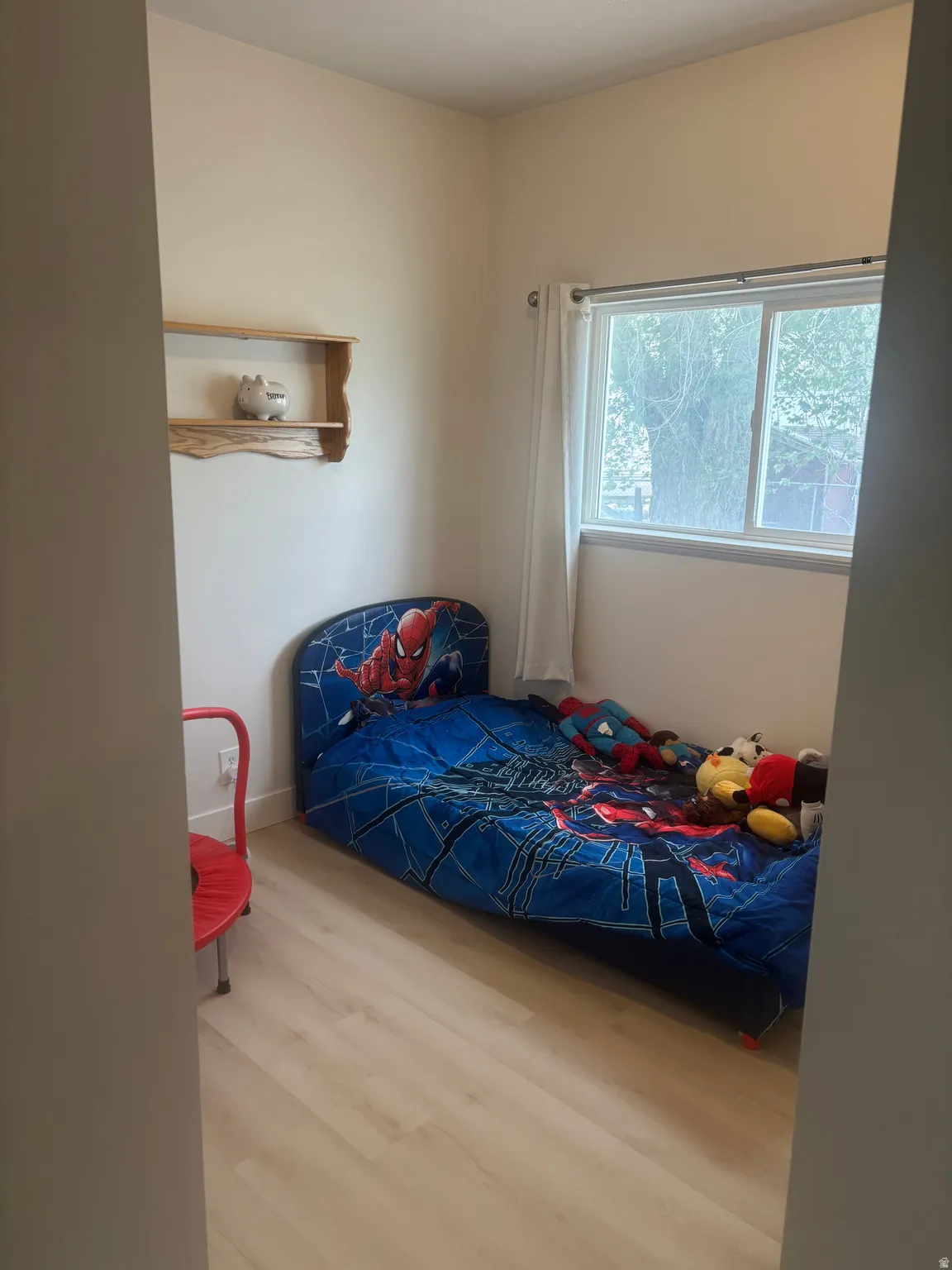 Light wood-finish flooring complements neutral wall tones with window and closet