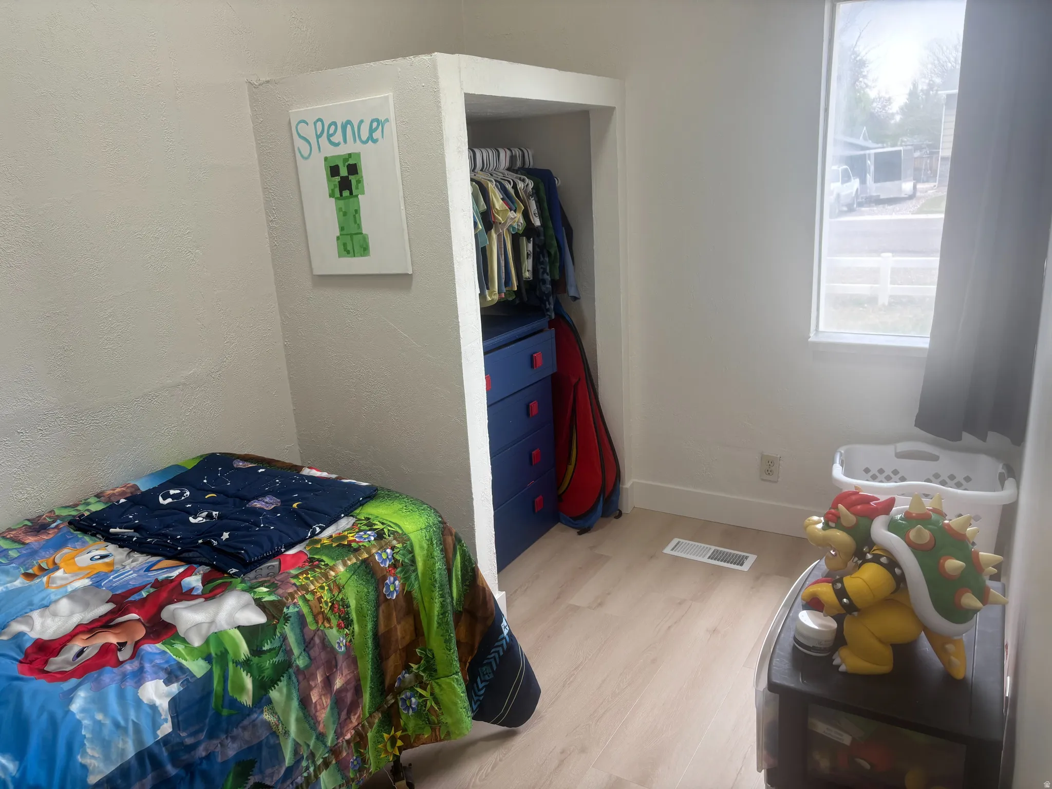 Room featuring light wood-finish flooring, a built-in closet with hanging space, and a window with white trim