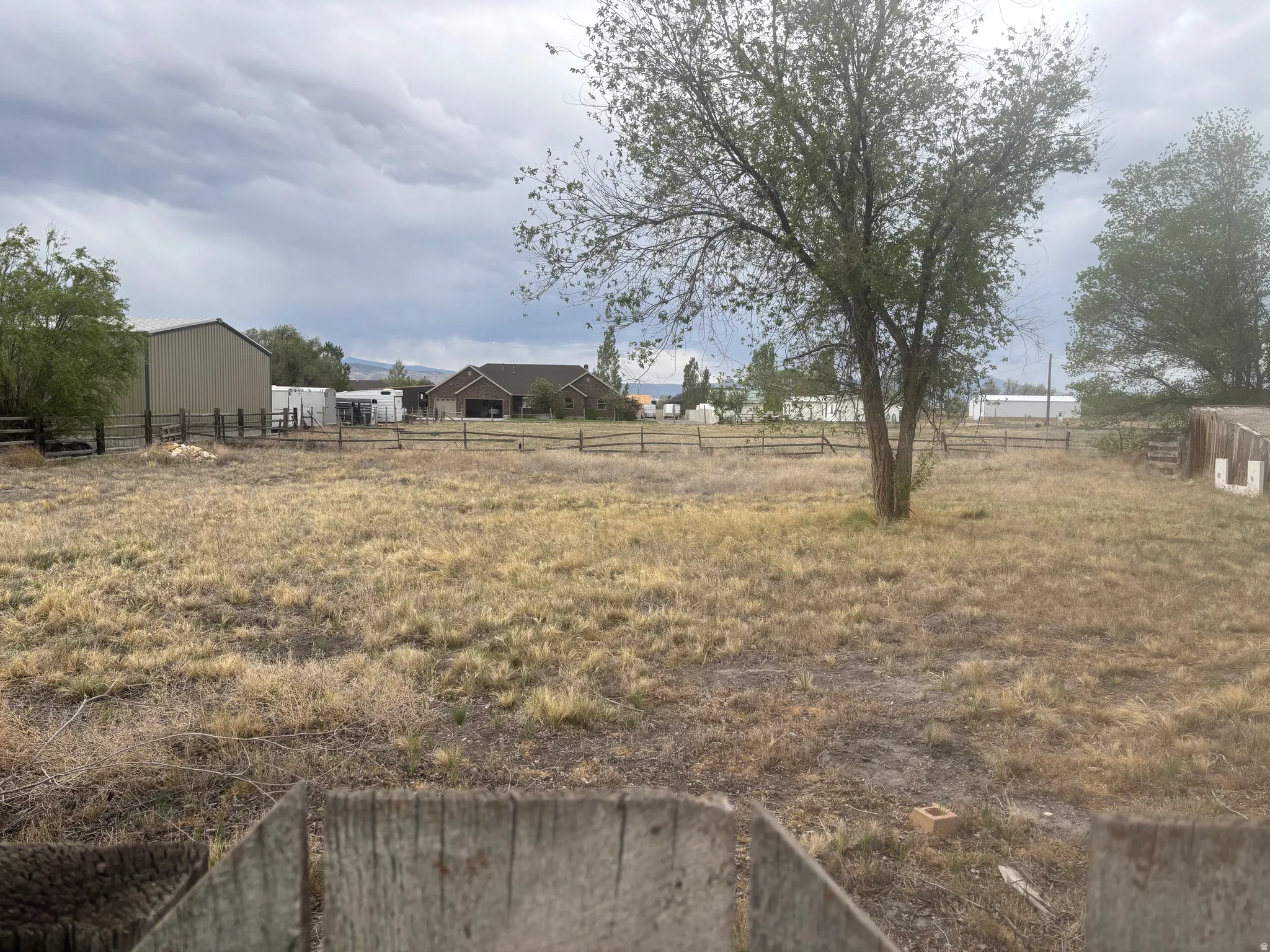 Expansive open land featuring mature trees and a rustic wood fence line