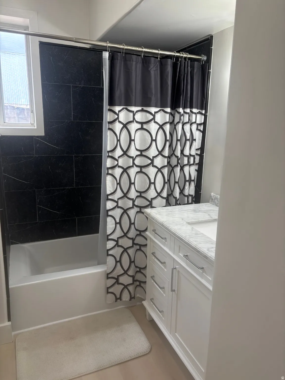 Bathroom featuring a white tub, dark tile shower surround, and a window