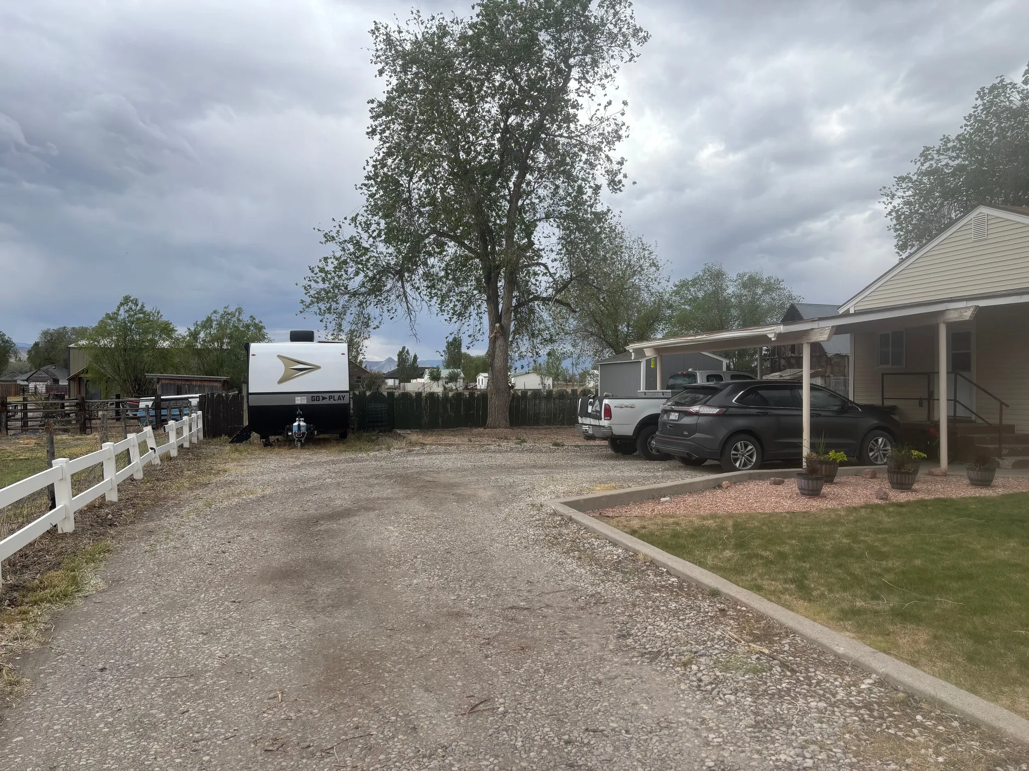 Gravel driveway leading to a carport and a side entry