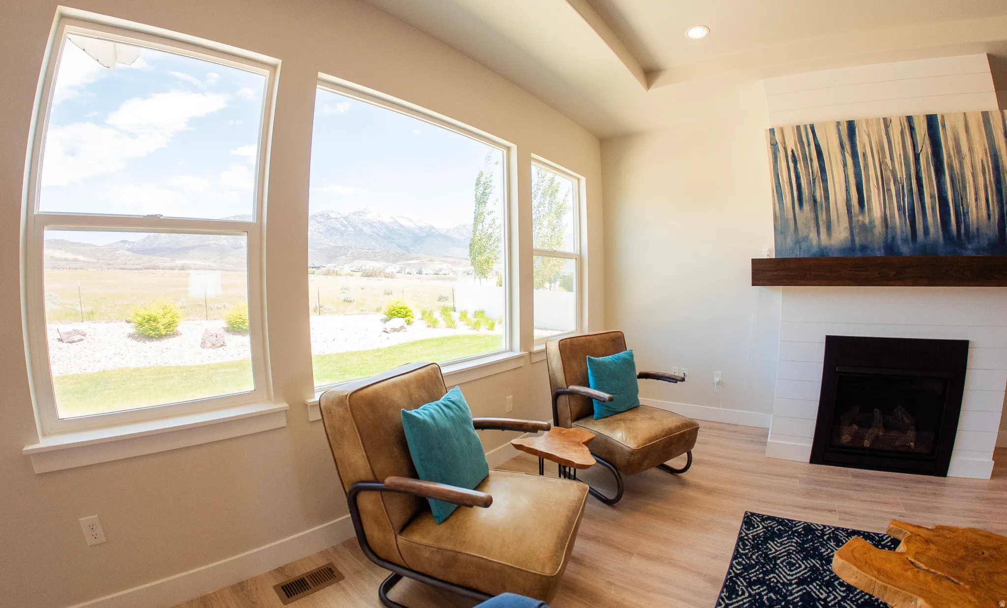 Living area featuring multiple large windows, wood-finish flooring, a built-in fireplace with white shiplap surround, and a dark wood mantel