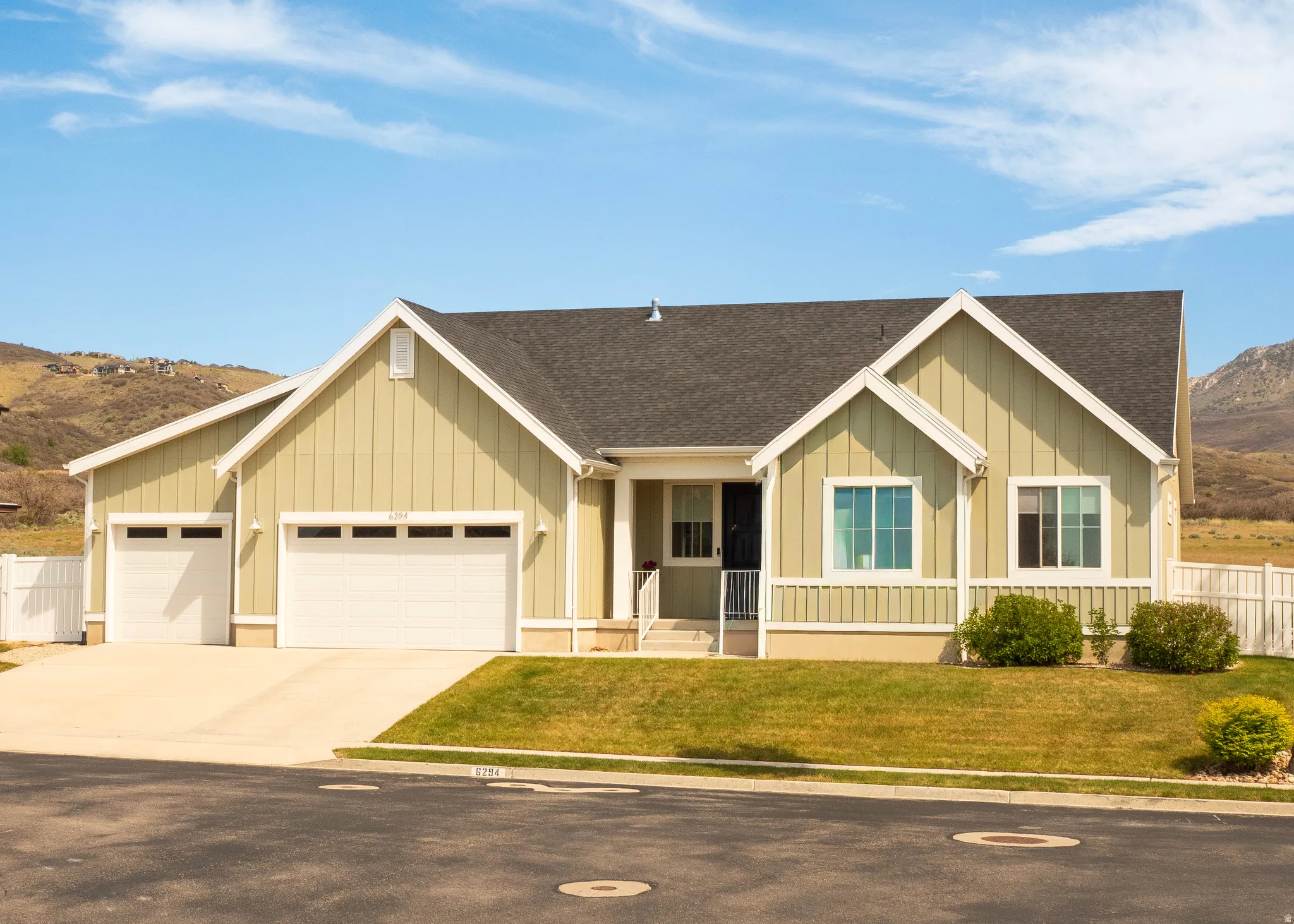 Contemporary ranch-style residence featuring a light green board and batten facade and a dark shingle roof