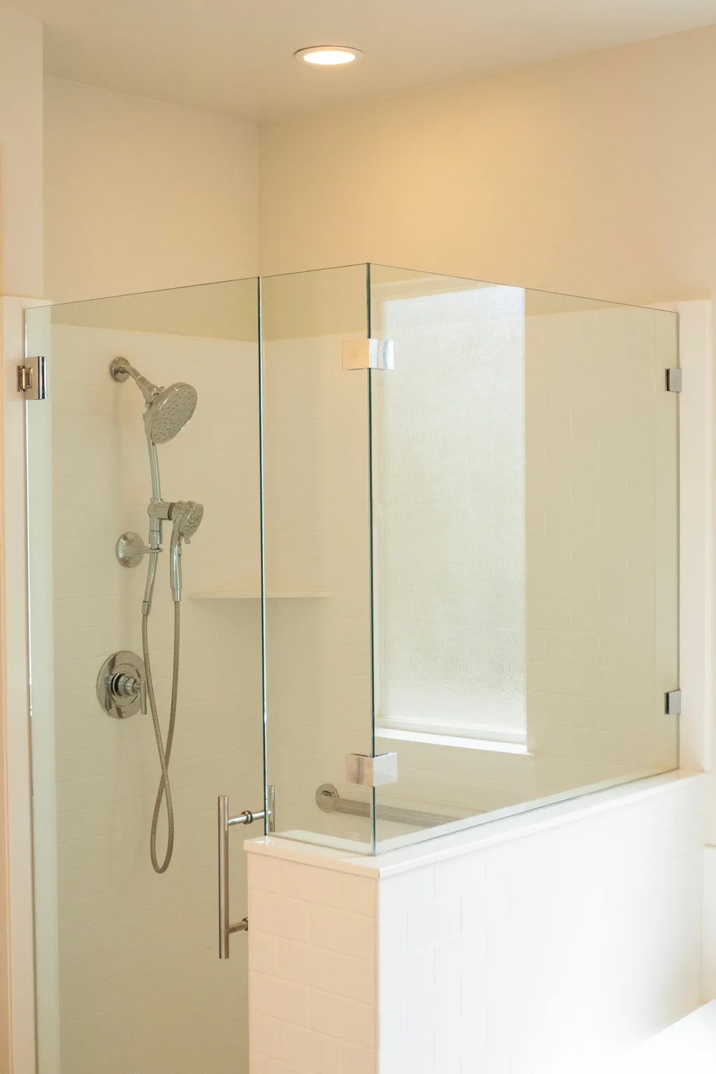 Glass-enclosed shower featuring a handheld showerhead and an integrated shelf