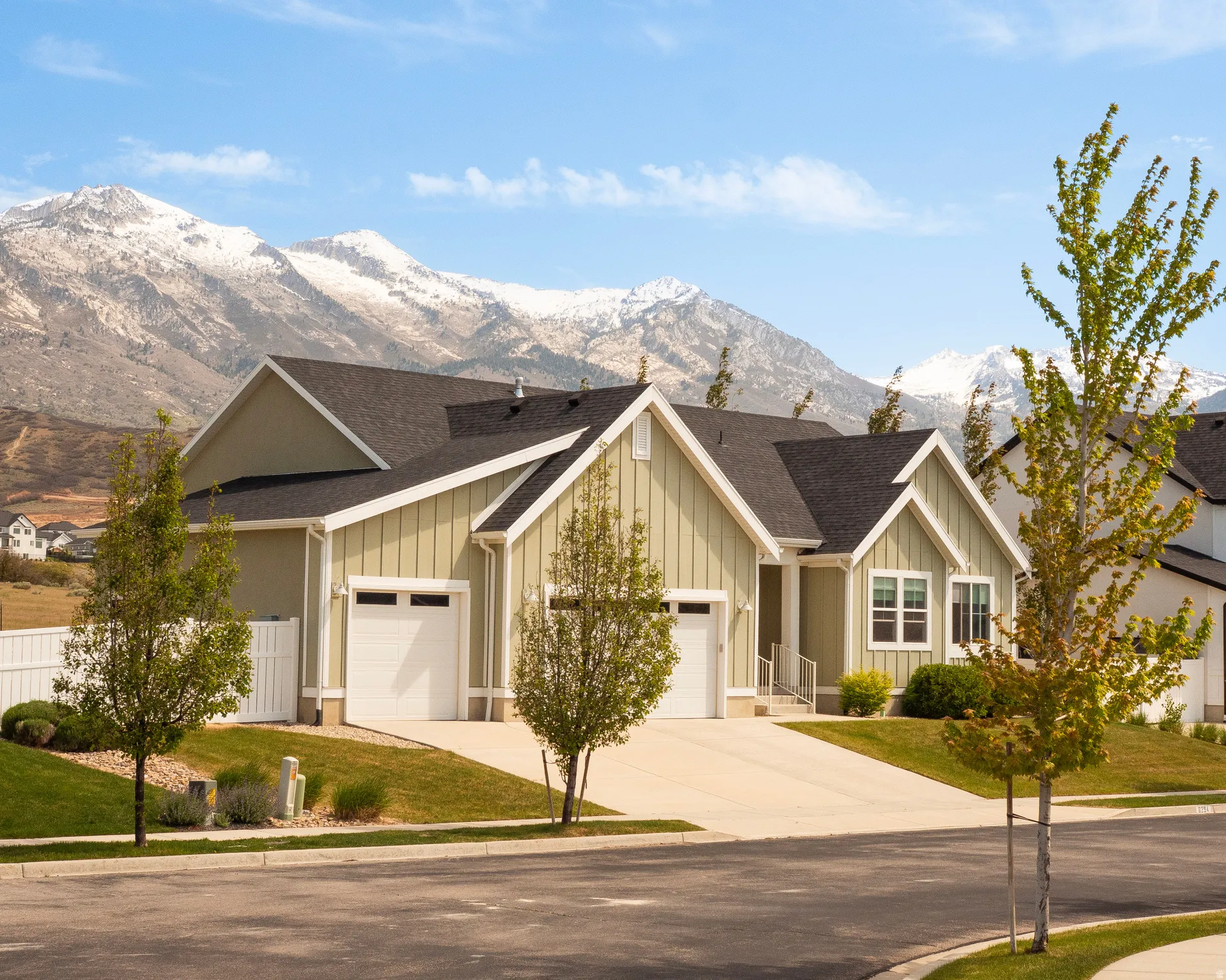 Contemporary home with light green vertical siding and dark shingle roofing