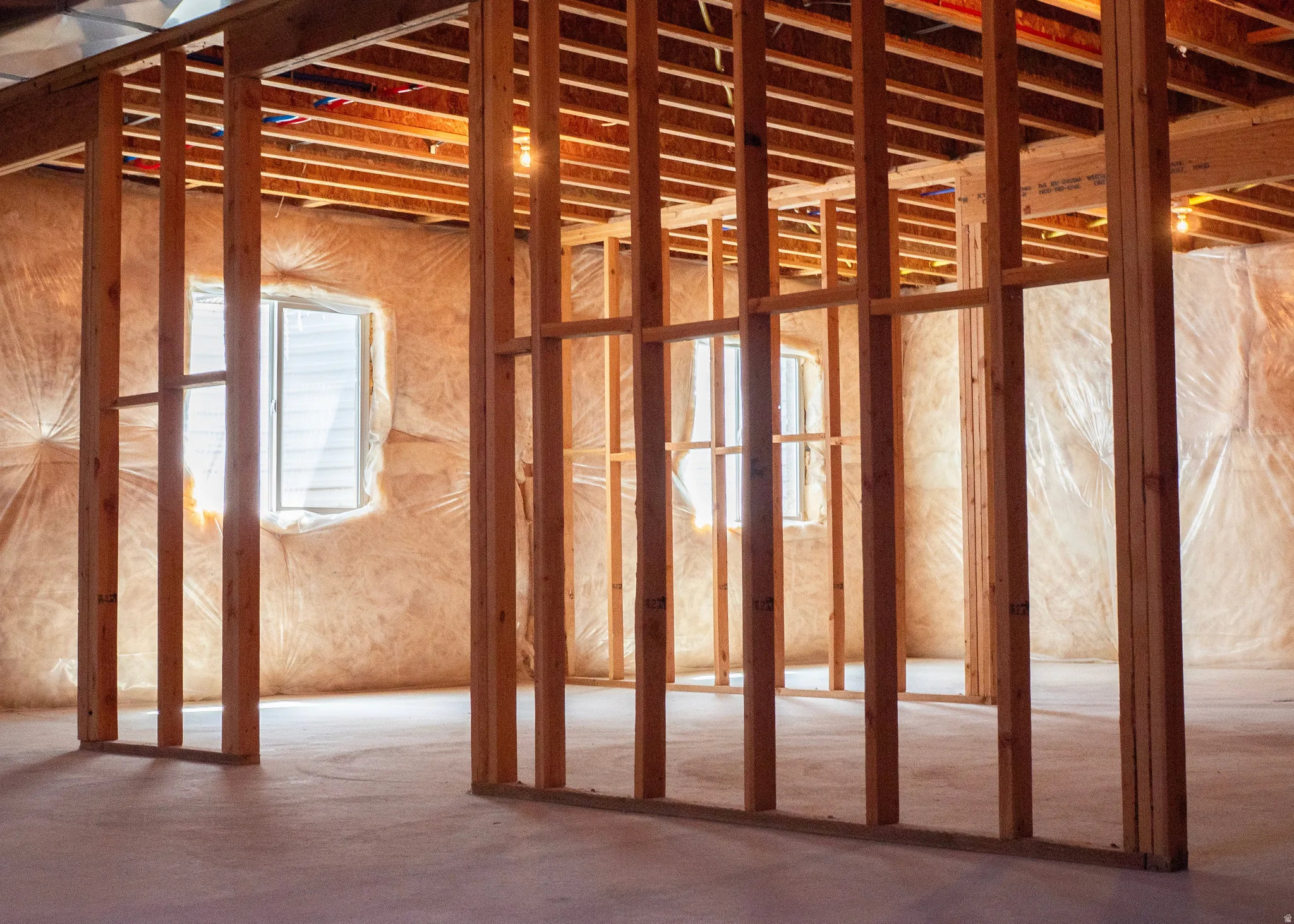 Unfinished interior space featuring exposed wood framing, concrete flooring, and multiple windows
