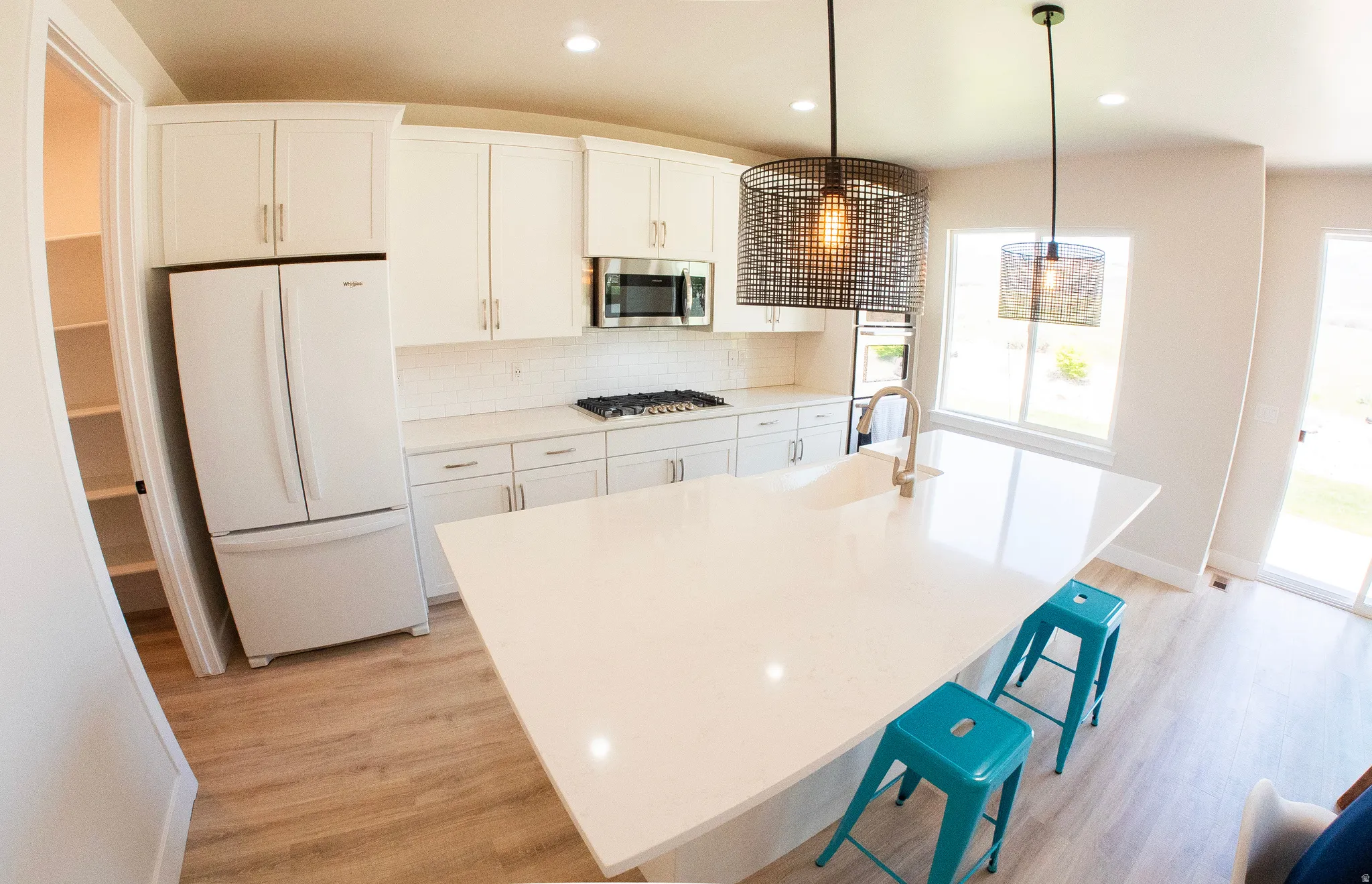 Contemporary kitchen featuring a large center island with integrated sink, white cabinetry, a built-in microwave, and a gas cooktop