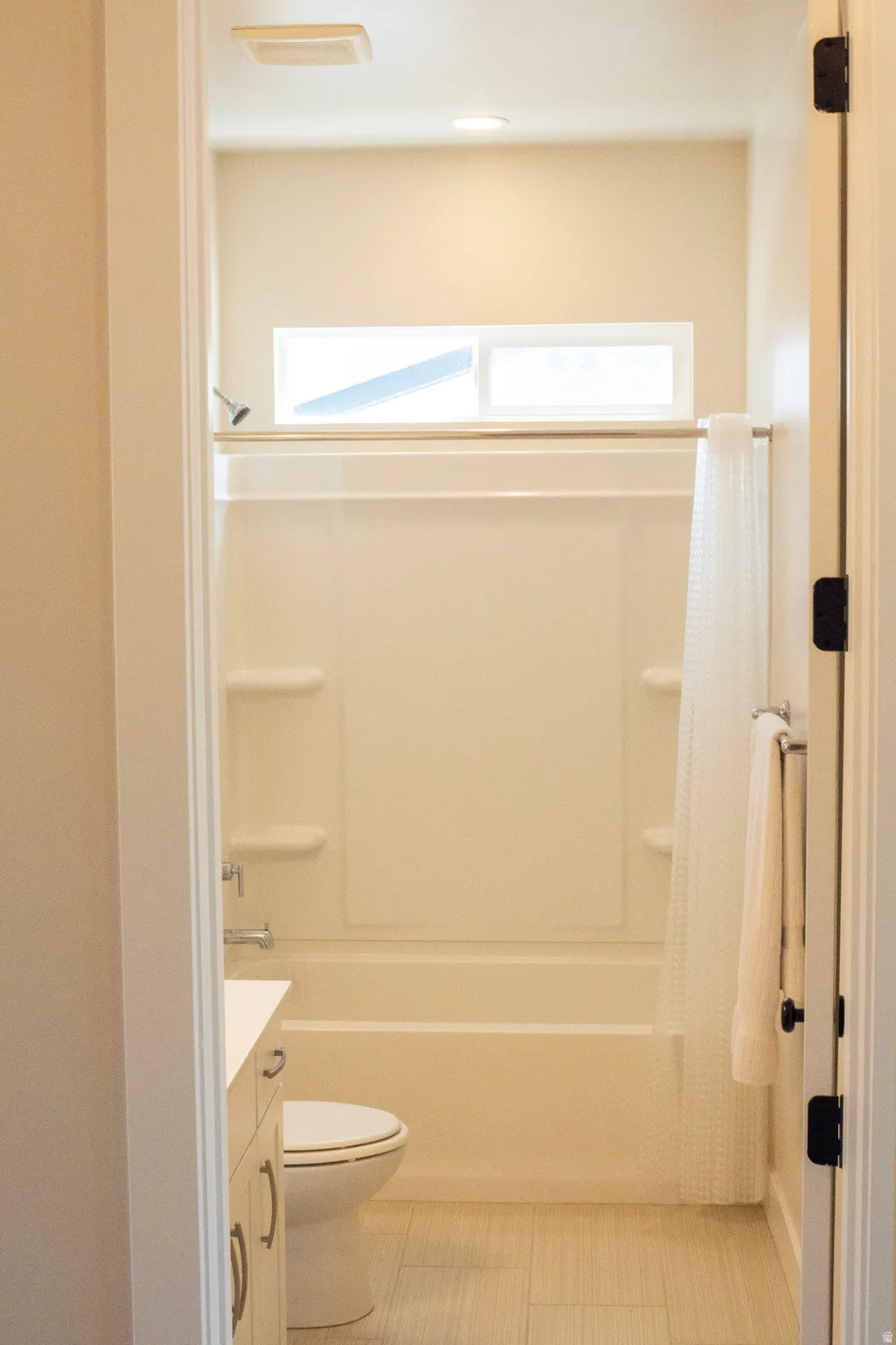 Bathroom featuring a combination shower and tub with a white surround and a transom window