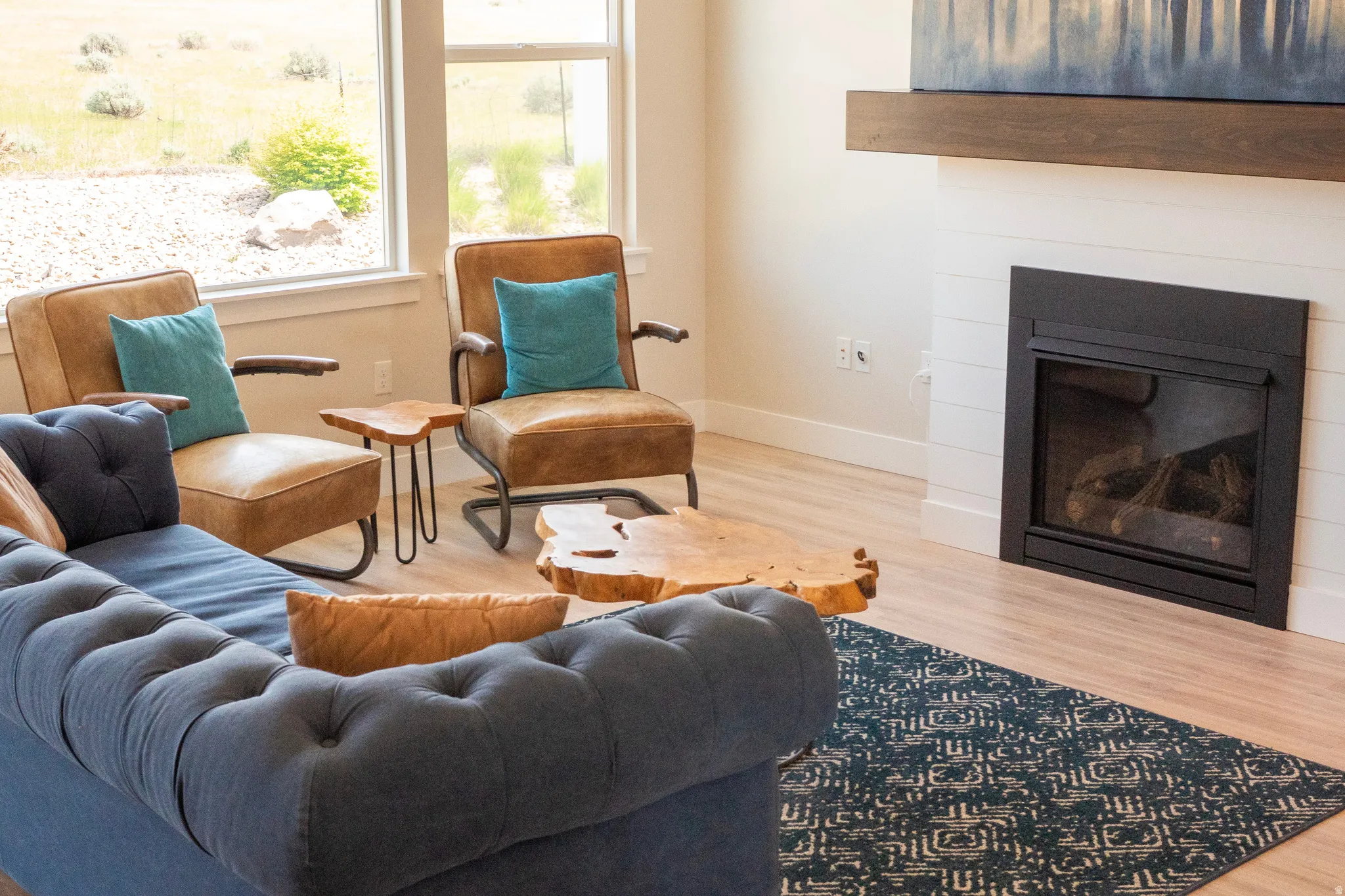 Living area featuring a modern fireplace with a dark metal surround, shiplap-style accent wall, and a wood mantel