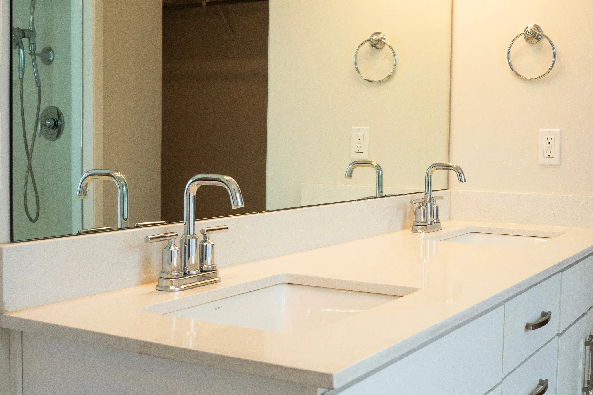 Dual undermount sinks set within a light-toned countertop, featuring chrome two-handle faucets