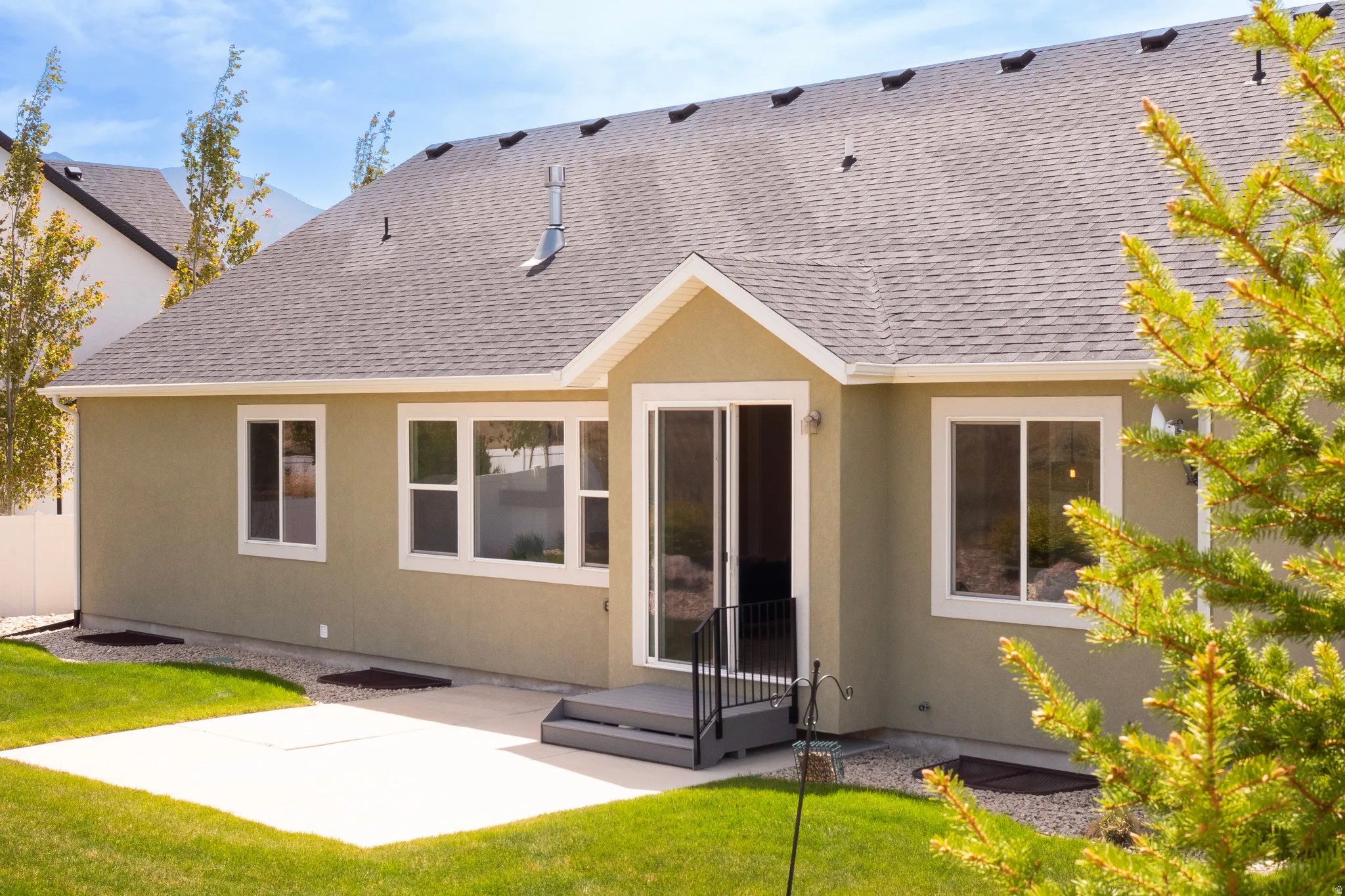Rear exterior featuring a concrete patio, sliding glass door, and multiple windows