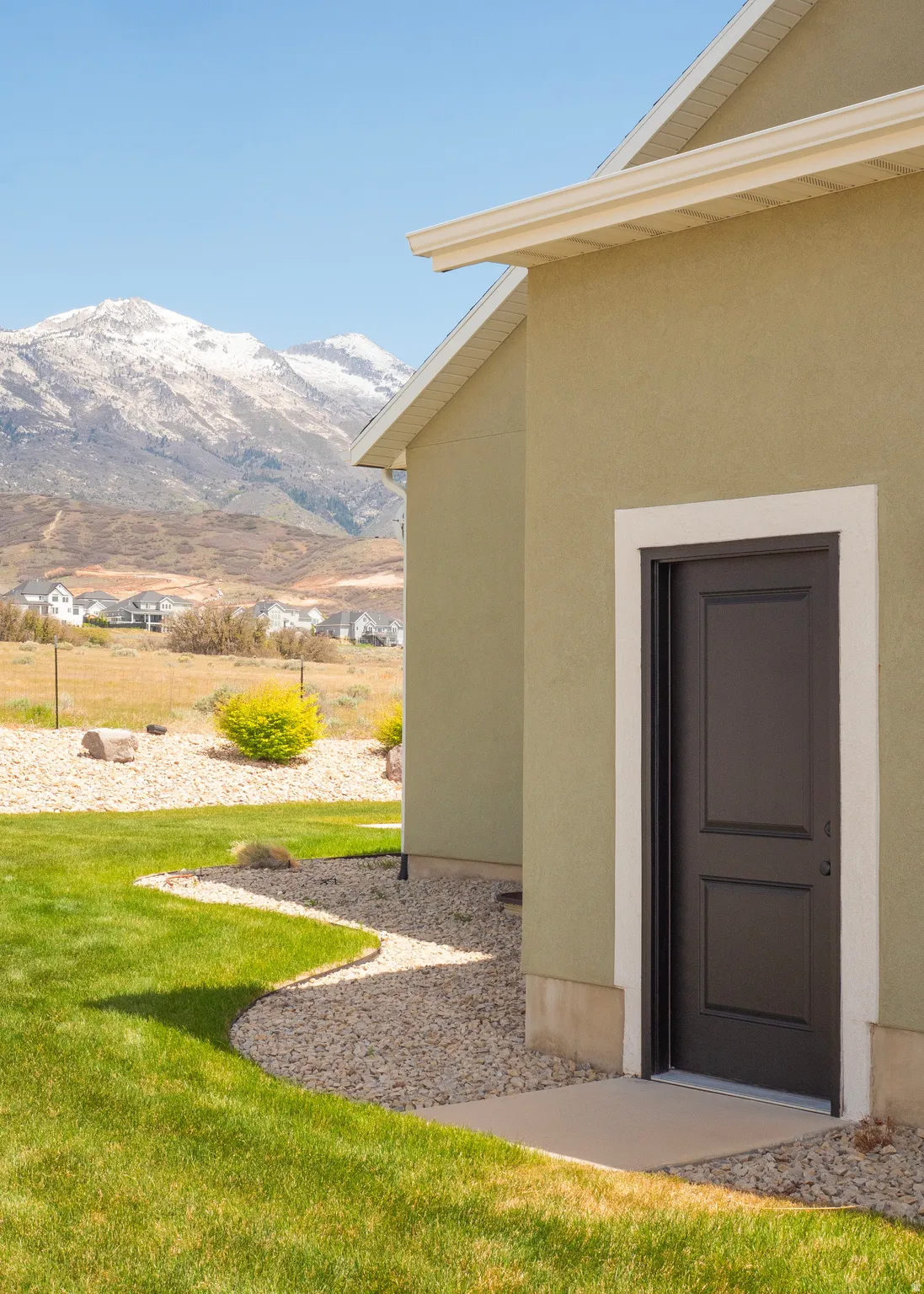 Stucco exterior with a dark-paneled door, framed by a concrete landing and gravel path