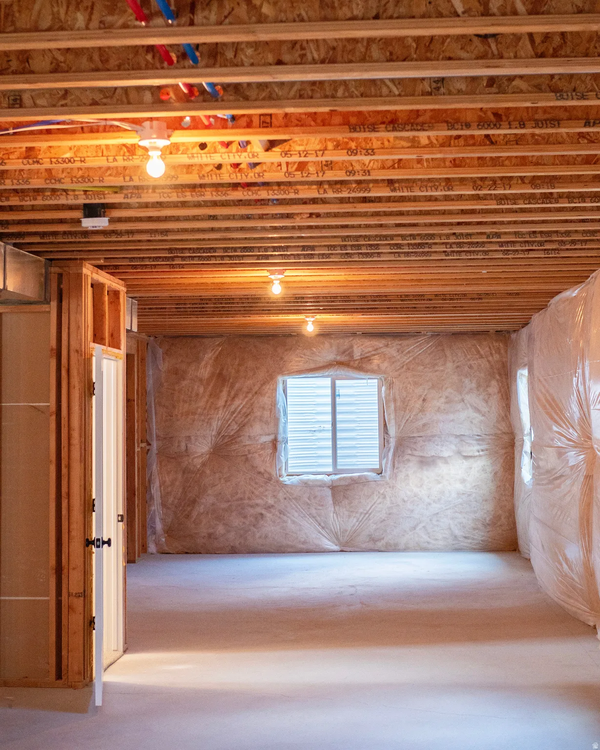 Unfinished basement space featuring exposed wood joists and subfloor ceiling