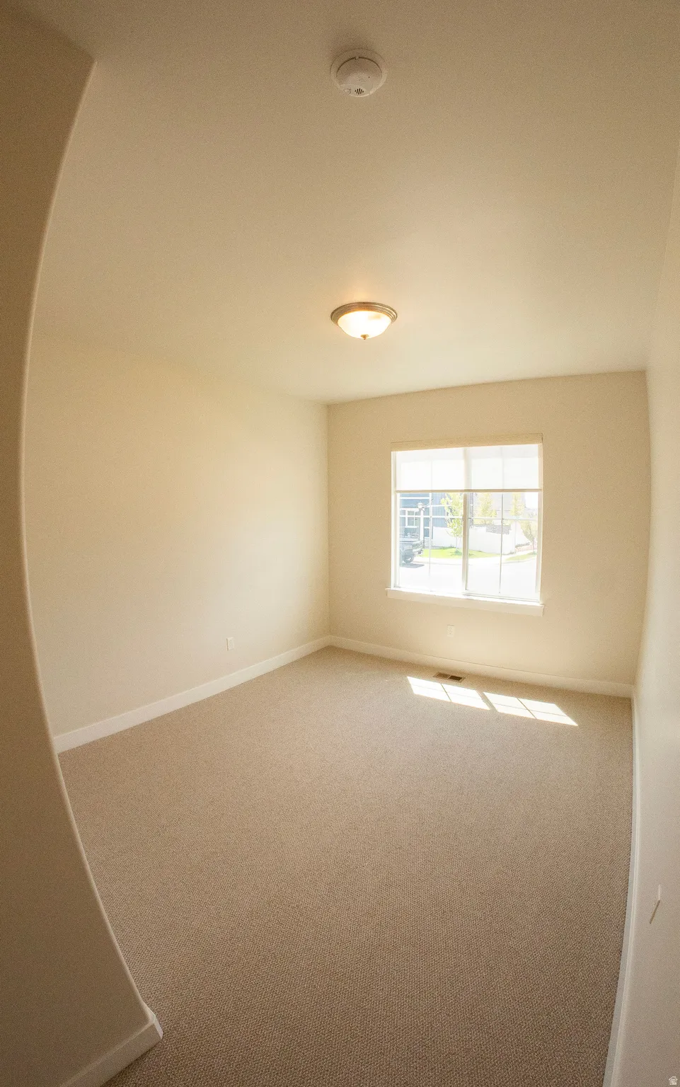 Carpeted room featuring a white-framed window, recessed ceiling light, and neutral wall tones
