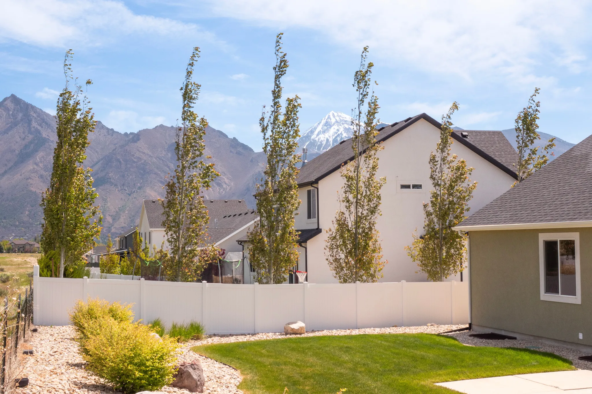 Expansive backyard featuring a manicured lawn, gravel landscaping, and mature shrubbery