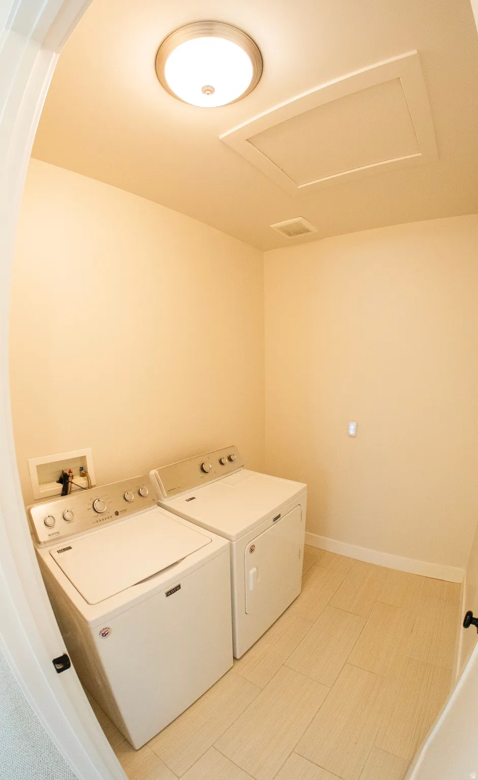 Dedicated laundry area featuring a washer and dryer, light-toned tile flooring, and neutral wall paint