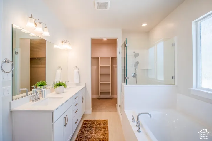 Dual vanity with undermount sinks, frameless glass shower enclosure, built-in bathtub, and an organized closet space