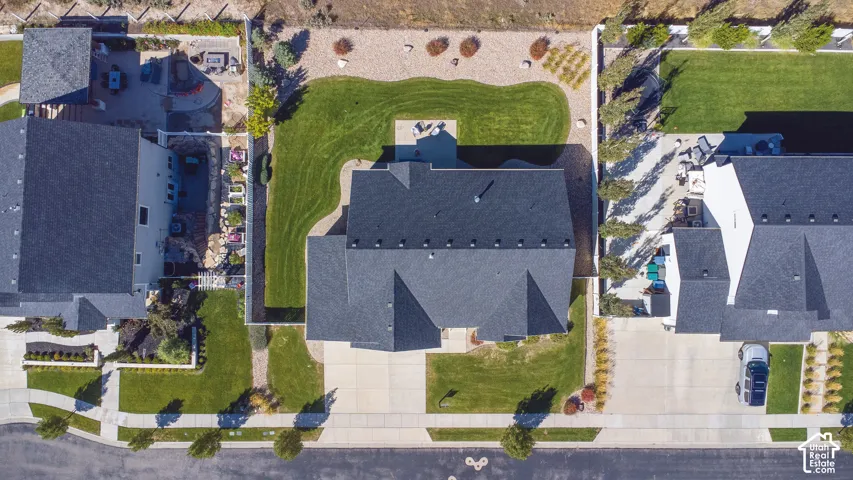 Expansive backyard featuring a manicured lawn, established landscaping, and a patio area