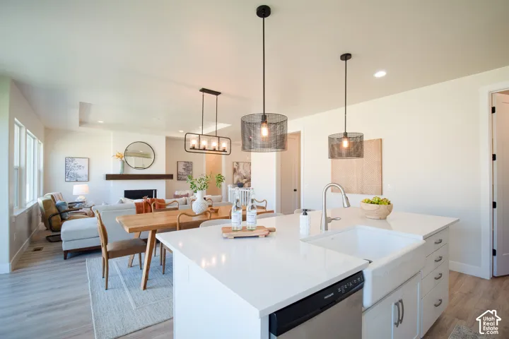Spacious open-concept living area featuring a kitchen island with a farmhouse sink, stainless steel dishwasher, and two pendant lights