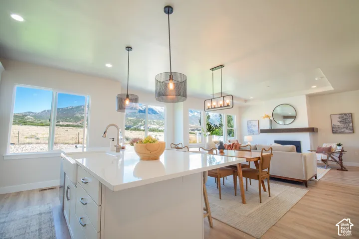 Open-concept living area featuring a kitchen island with integrated sink, wood-finish flooring, a contemporary fireplace, and recessed lighting