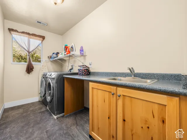 Dedicated laundry space featuring slate-style flooring, a window, built-in cabinetry, a utility sink, and a countertop