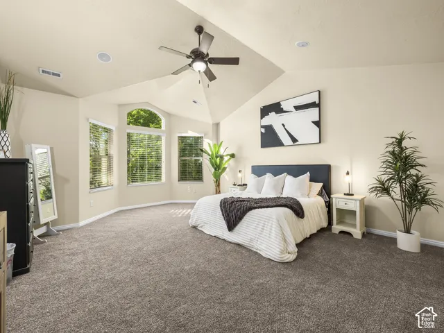 Spacious room featuring vaulted ceilings, recessed lighting, a ceiling fan, bay windows with blinds, and neutral-toned carpeting