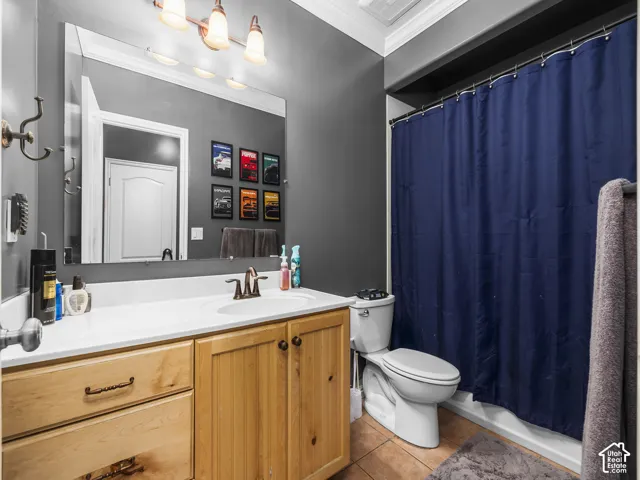 Bathroom featuring a wood-finish vanity with a white countertop and integrated sink, a large wall-mounted mirror, a three-light vanity fixture, and tiled flooring