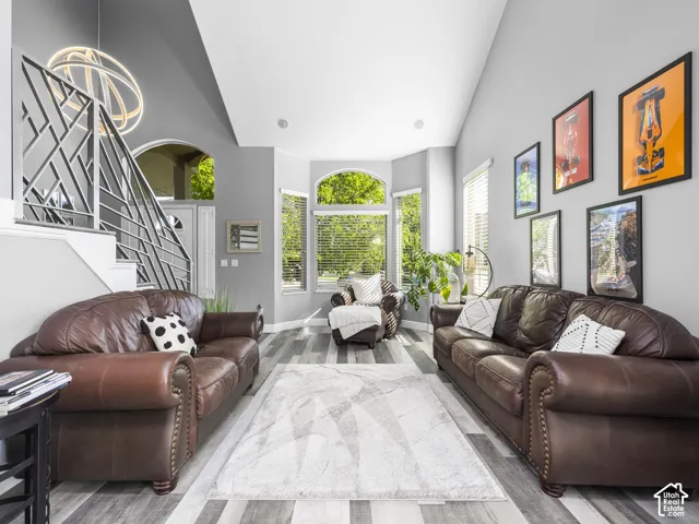 Vaulted ceiling living area featuring wood-finish flooring and a modern geometric staircase railing